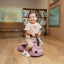 Niño feliz sentado en el correpasillos Globber Walk n Roll 2 en 1 Ecologic Berry