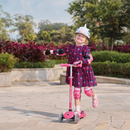 Niña con casco andando en el Globber Go Up Sporty Lights Dark Pink en modo scooter