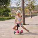 Niña sentada impulsándose con los pies en el Globber Go Up Sporty Lights Dark Pink en modo correpasillos libre