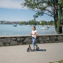 Niña andando en el scooter Globber NL 205 Black Grey junto al lago